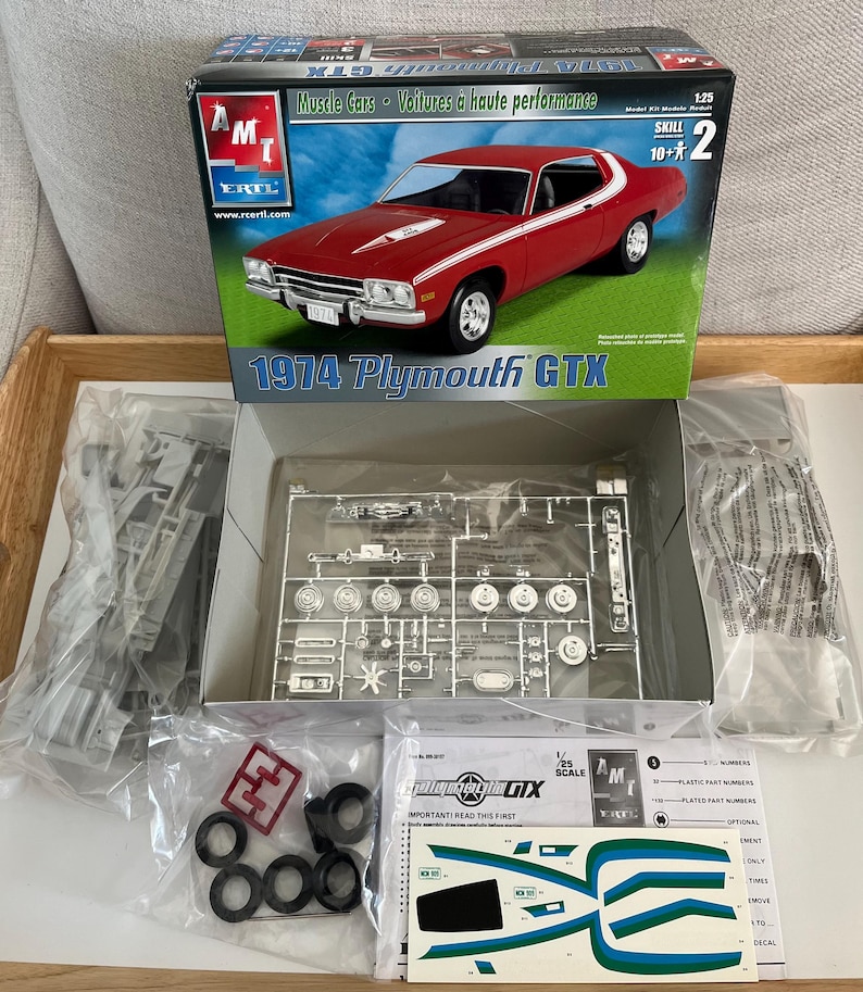 Puede incluir: Un kit de maqueta de coche de carreras Plymouth GTX 1974 a escala 1/25. El kit est&aacute; en su embalaje original e incluye un coche modelo rojo y blanco, una grapa de pl&aacute;stico transparente y una hoja de calcoman&iacute;as. La caja est&aacute; etiquetada con el logotipo de AMT/ERTL y las palabras "Muscle Cars" y "Voitures &agrave; haute performance".