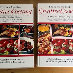May include: Two identical hardcover cookbooks titled "The Encyclopedia of Creative Cooking" by Charlotte Turgeon. The books feature a colorful collage of food photos on the cover, including stuffed tomatoes, roasted meat, and a bowl of fruit.