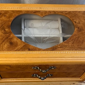 May include: A wooden jewelry box with two drawers and a heart-shaped glass lid. The lid has a floral design etched into it.