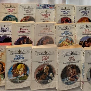 Pode incluir: Uma coleção de romances de bolso vintage. Os livros apresentam títulos como "Clear Villain", "Twisting Shadows" e "Silence Speaks for Love". Cada livro tem uma ilustração de capa única com um tema romântico.