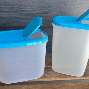 Könnte beinhalten: Zwei durchsichtige Plastikbehälter mit blauen Deckeln. Die Deckel haben ein Klappdesign für einfachen Zugang.