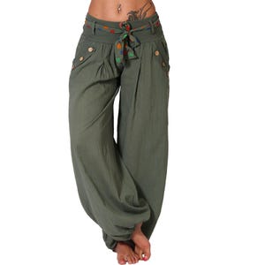 Könnte beinhalten: Grüne weite Hose mit einem bunten Gürtel und Knopfdetails.