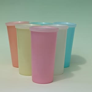 May include: Six pastel-coloured plastic tumblers with matching lids. The tumblers are arranged in a semi-circular pattern, displaying shades of pink, yellow, white, and blue. The lids are a lighter shade of the tumbler's colour.