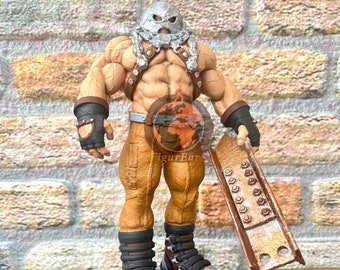 Könnte beinhalten: Eine muskulöse Actionfigur mit silbernem Helm, gebräunter Haut und brauner Hose, die schwarze Handschuhe und Stiefel mit silbernen Nieten trägt. Die Figur hält einen braunen Metallträger und steht auf einem runden blauen Sockel mit silbernen Nieten.
