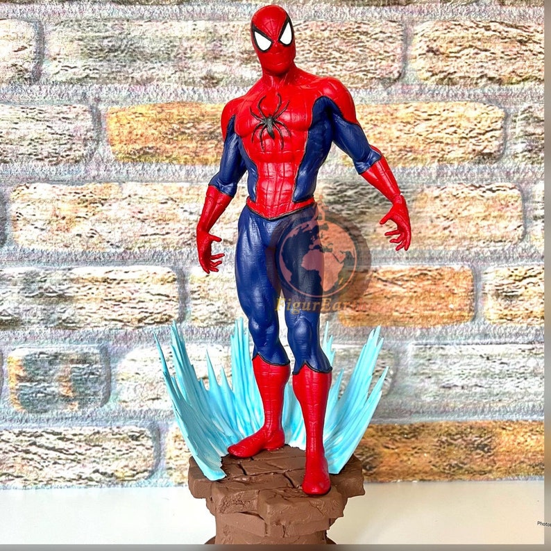 May include: A red and blue Spider-Man action figure stands on a brown base with a blue and white effect around the base. The figure is posed with its arms outstretched and its head tilted slightly to the side.