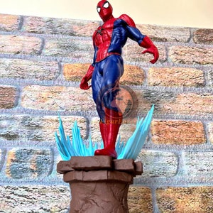 May include: A red and blue action figure of Spider-Man standing on a brown base with blue and white spiky accents. The figure is posed with one arm raised and the other at his side.