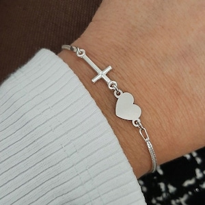 May include: A silver bracelet with a cross charm and a heart charm.