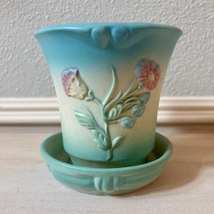 以下が含まれることがあります： ヴィンテージの陶器製の植木鉢と受け皿のセット。 植木鉢は、ピンクとクリーム色の花柄のライトブルーです。 受け皿も同じライトブルーです。 植木鉢はフレア型です。
