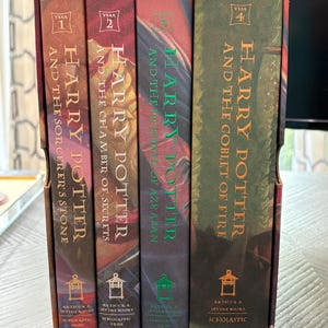 May include: A four-book Harry Potter boxed set featuring the first four titles: The Sorcerer's Stone, The Chamber of Secrets, The Prisoner of Azkaban, and The Goblet of Fire. Each book spine displays the author Rowling, the year, and the title.