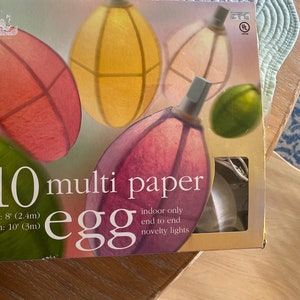 Peut inclure: Une boîte de 10 lumières de fête en forme d'œuf en papier multicolores. Les lumières mesurent 2,4 mètres de long et sont uniquement destinées à un usage intérieur. La boîte porte un label de certification de sécurité UL.