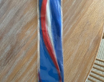 Extensão de cabelo com presilha nas cores patrióticas, mecha vermelha, branca e azul.