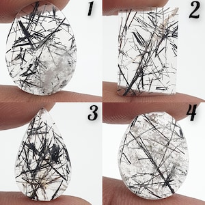 Puede incluir: Cuatro piedras preciosas de cuarzo transparente con inclusiones de turmalina negra. Las piedras preciosas tienen diferentes formas: ovalada, rectangular, en forma de lágrima y otra ovalada. Las inclusiones negras crean un contraste llamativo.