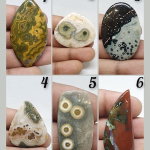 Puede incluir: Seis tipos diferentes de cabujones de ágata, cada uno con patrones y colores únicos. Los cabujones se muestran sobre un fondo blanco con los números del 1 al 6.
