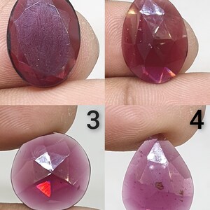 Pode incluir: Quatro pedras preciosas facetadas em tons de magenta profundo e roxo. O número 1 é oval, o número 2 é um oval irregular, o número 3 é redondo e o número 4 tem formato de pera. Cada pedra tem uma superfície polida com facetas geométricas.