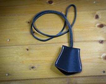 Könnte beinhalten: Ein schwarzer Leder-Schlüsselanhänger mit einem kleinen Beutel und weißen Nähten. Der Schlüsselanhänger liegt auf einer Holzoberfläche.