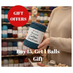 Könnte beinhalten: Eine teal- und braune YarnArt Macrame Cotton Spectrum Garnkugel wird vor einem Regal mit farbenfrohem Garn gehalten. Der Text "GIFT OFFERS" befindet sich in einem roten Kreis. Der Text "Buy 15, Get 1 Balls Gift" steht darunter.