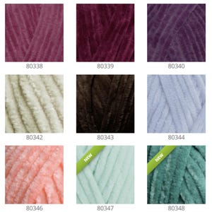 May include: A collection of ten yarn skeins in various colors, including burgundy, purple, cream, brown, light blue, peach, and green. The yarn is soft and fluffy, with a fuzzy texture. The skeins are labeled with numbers, such as 80338, 80339, 80340, and so on.
