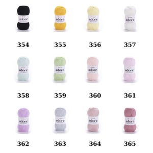 Puede incluir: Una colecci&oacute;n de 10 ovillos de lana en varios colores, incluyendo negro, amarillo, verde claro, rosa y gris. Cada ovillo est&aacute; etiquetado con "adore" y tiene un n&uacute;mero correspondiente del 354 al 365.