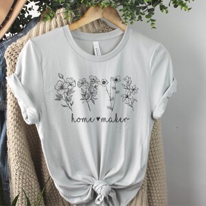 May include: A light gray t-shirt with a black floral design and the text "home &hearts; maker" printed on the front.