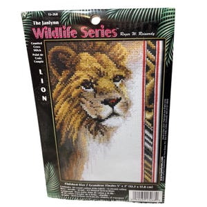 May include: A cross stitch pattern featuring a lion's face. The pattern is titled "The Janlynn Wildlife Series" and is by Roger W. Reinardy. The finished size is 5 inches by 7 inches (12.7 cm by 17.8 cm).