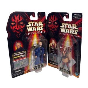 Könnte beinhalten: Zwei Star Wars Episode I Actionfiguren-Verpackungen. Eine zeigt Senator Palpatine in einem blauen Gewand, die andere eine Figur in einem beige-roten Outfit. Die Verpackung hat rote und schwarze Grafiken.