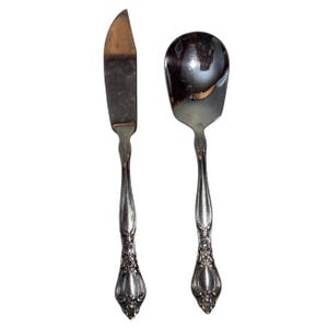 Könnte beinhalten: Ein Set aus zwei versilberten Servierbesteck, ein Buttermesser und ein Zuckerlöffel, mit verzierten Griffen.