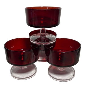 Könnte beinhalten: Set aus vier roten Glasschalen für Desserts mit klaren Glasstielen und -sockeln.