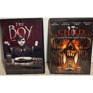 May include: Two DVD movie cases. The first is titled "The Boy" with a dark image of a young person. The second is titled "13th Child" with a demonic skull image. Both cases have text and are on a light surface.