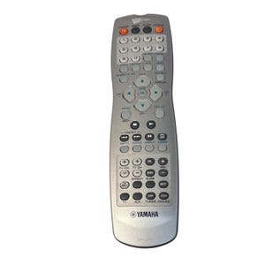 May include: Silver Yamaha remote control with numerous buttons for TV and audio functions. Features buttons for power, volume, channel selection, and menu navigation. The remote has a curved bottom and the Yamaha logo.