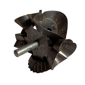 May include: A vintage metal biscuit cutter tool featuring a central cylindrical handle attached to a rotating hub with multiple distinct shapes, including heart and fluted designs, showing signs of oxidation and wear on the metallic surface.
