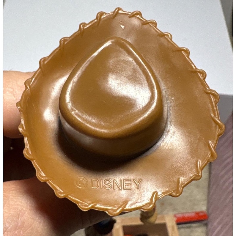Puede incluir: Un sombrero de vaquero marr&oacute;n con un ala cosida y una corona redondeada. El sombrero est&aacute; hecho de un material liso y brillante. La palabra "DISNEY" est&aacute; impresa en la parte inferior del sombrero.