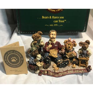 May include: A Boyd's Bearstones Fifth Anniversary figurine depicting a man and several teddy bears. The bears are dressed in various outfits, and the figurine includes a box and a booklet. The box reads "Bears & Hares you can Trust".