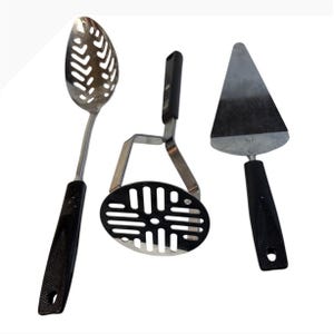 Può includere: Un set di tre utensili da cucina con manici in plastica nera e impugnature testurizzate. Il set include un cucchiaio forato argentato, uno schiacciapatate argentato con design a griglia rettangolare e una paletta per torte triangolare.