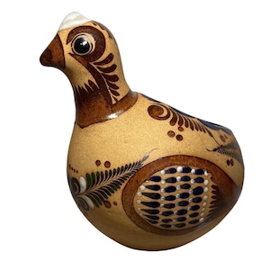 Puede incluir: Figura de pájaro de cerámica con cuerpo beige y detalles decorativos marrones. El pájaro tiene una cresta blanca, un pico marrón y patrones detallados en su cuerpo, incluyendo diseños florales y de puntos. El ojo del pájaro es negro con un reflejo blanco.