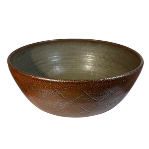 May include: A handmade ceramic bowl with a diamond pattern on the exterior. The bowl has a brown exterior and a gray interior. The rim has a textured, speckled appearance. This bowl is suitable for serving food.