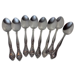 Könnte beinhalten: Set aus zehn silbernen Teelöffeln mit verzierten Griffen. Die Löffel haben ein klassisches Design und sind perfekt für den täglichen Gebrauch.