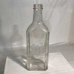 Può includere: Una bottiglia di vetro trasparente con una superficie testurizzata. La bottiglia è etichettata "Burdock Blood Bitters".