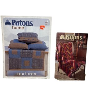 Könnte beinhalten: Zwei Strickmusterbücher von Patons. Das erste Buch zeigt eine blaue und braune gestrickte Wolldecke mit dem Text "textures". Das zweite Buch zeigt eine rote, gelbe und violette gestrickte Wolldecke mit dem Text "Canadiana at home".