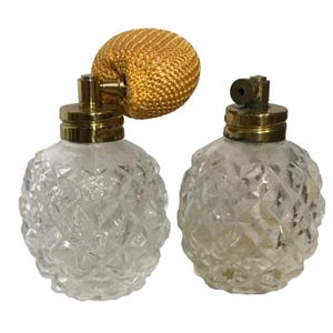 May include: Two vintage glass perfume atomisers with gold tops and a textured diamond pattern. One atomiser has a gold fabric puff attached to the top.