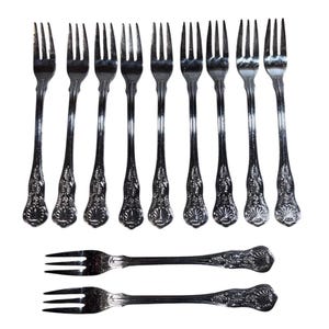 May include: An assortment of silver forks with decorative handles. The forks are displayed in two rows, with the tines facing upwards in the top row and horizontally in the bottom row. The handles have a detailed floral and shell pattern.