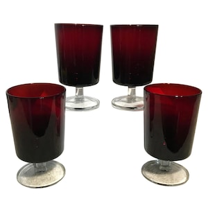 May include: Set of four red glass stemmed drinking glasses. The glasses have a clear base and a dark red body.