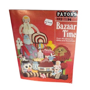 Puede incluir: Portada roja de un folleto vintage Patons "Bazaar Time", que muestra manualidades de punto y ganchillo. El texto de la portada dice "Bazaar Time" y "Más de 40 ideas para regalos y novedades". La imagen muestra varios artículos hechos a mano, incluyendo una muñeca, un búho y un león.