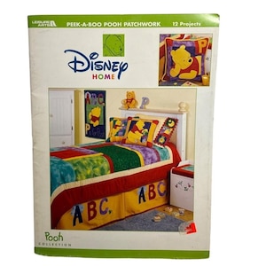 Op de afbeelding: Een boekomslag voor een Disney Home Peek-A-Boo Pooh Patchwork quiltproject. De omslag toont een kleurrijk patchwork quilt met Winnie de Poeh-personages en ABC-letters. Het boek bevat 12 projecten.