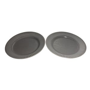 Puede incluir: Dos platos ovalados de cerámica gris. Cada plato tiene un centro sólido y un borde con líneas verticales espaciadas uniformemente. Los platos están sobre un fondo blanco.