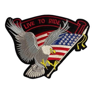 Può includere: Toppa ricamata con un'aquila calva e la bandiera americana. La toppa presenta la scritta "LIVE TO RIDE" in rosso su uno stendardo nero. L'aquila ha piume grigie e bianche, artigli gialli e un becco giallo.