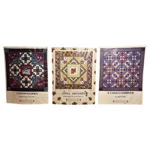 May include: Three quilt patterns, "Canyon Echoes", "Apple Orchard", and "A Calico Sampler", each featuring a different design and colour scheme. The patterns are printed on white paper with a border of red and white flowers.