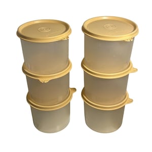 Puede incluir: Seis recipientes Tupperware vintage. Los recipientes son cilíndricos con un cuerpo translúcido y una tapa de color amarillo claro. Las tapas tienen un diseño circular en el centro. Los recipientes están apilados en dos grupos de tres.