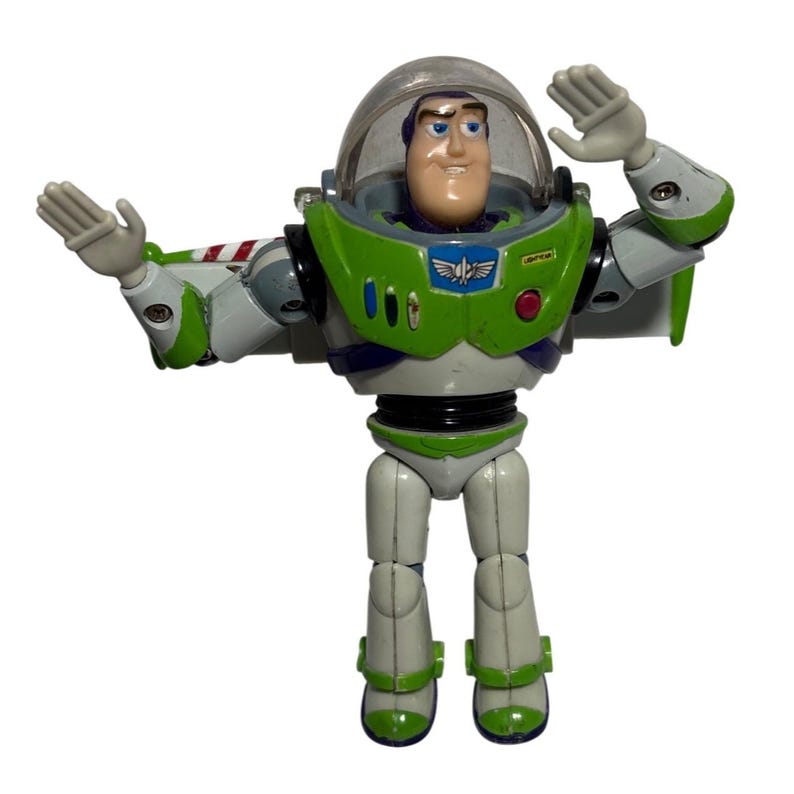 May include: A Buzz Lightyear action figure, featuring a green and white spacesuit with a clear helmet. The figure has its arms raised, showcasing its wings. The toy is a collectible item from the Toy Story franchise.