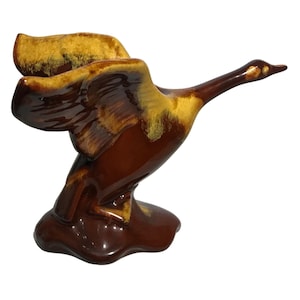 Peut inclure: Une figurine de canard en céramique émaillée brune et jaune avec les ailes déployées en vol. Le canard est perché sur une petite base.