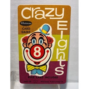 May include: Vintage Crazy Eights card game. The card features a cartoon clown with a blue hat and a red number 8. The card has the text "Crazy Eights" and "Whitman Card Game". The card is a retro design with a colorful background.